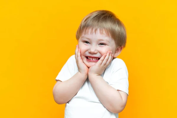 Πορτραίτο του εύθυμου μικρού αγοριού τριών ετών, που στέκεται απομονωμένο σε κίτρινο φόντο. Κοιτάζω την κάμερα. δείχνοντας λευκά δόντια, χαμογελαστά — Φωτογραφία Αρχείου