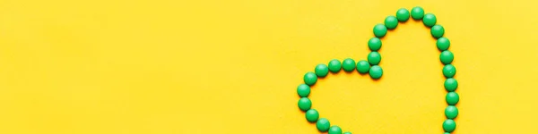 Zöld kerek tabletták tabletta szív alakú a yuellow háttér — Stock Fotó