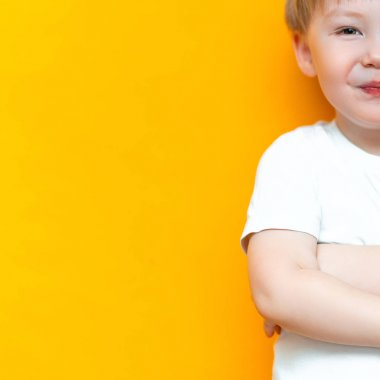 Sarı saçlı ve yeşil gözlü sarı arka plan üzerinde gülümseyen mutlu çocuk portresi 3 yaşında karışık ırk yarı Asya yarı Kafkas
