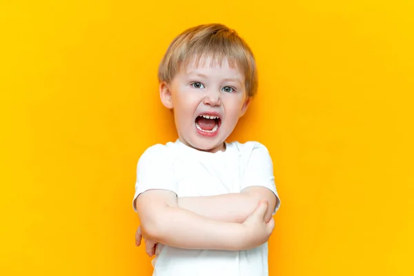 Cue little niño de 3 años de pie y la boca abierta hos gritar en voz alta, los brazos doblados en el pecho, en camiseta blanca — Foto de Stock