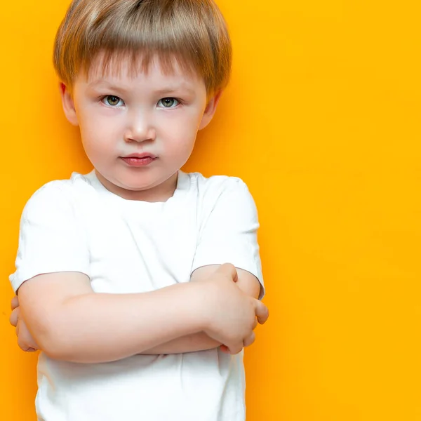 Πορτρέτο του θυμωμένο αγοράκι με χέρια διπλωμένα απομονωμένα σε κίτρινο φόντο. Θλιβερό και δυστυχισμένο παιδί. Αναστατωμένος νήπιο αγόρι — Φωτογραφία Αρχείου