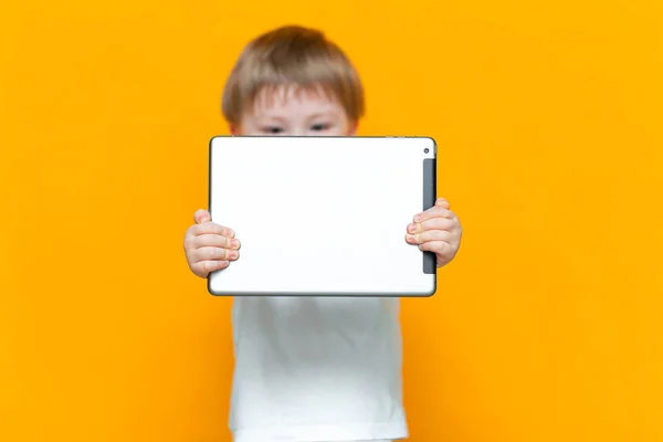 Mezclado racial rubia chico usando tableta pc en amarillo fondo — Foto de Stock