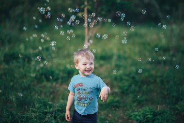 Sevimli erkek çocuk doğada üç yıl eski sarışın saç sabun kabarcıklar yakalar