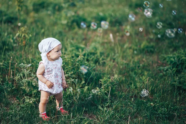 작은 소녀는 비누 거품, 봄 초상화 아름 다운 1 년 오래 된 아이를 불고 — 스톡 사진