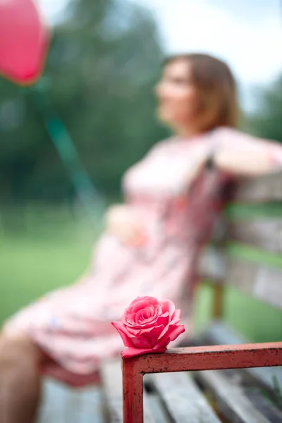 Wanita hamil menyentuh benjolan sementara memegang gadis mawar merah muda menunggu — Stok Foto