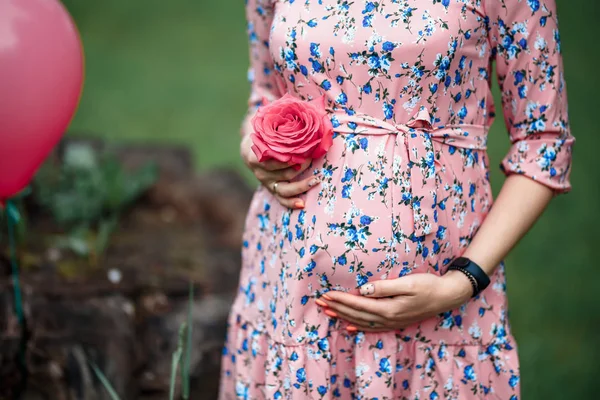 Pregnant woman touching bump whilst holding pink rose girl waiting — Stock Photo, Image