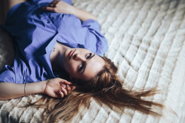 Mavi büyük gözlü seksi genç güzel kadın mavi gömlek evde yatakta yatan tek saç lond