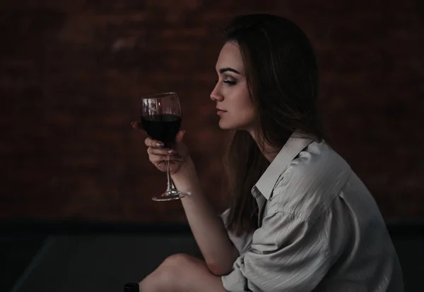 Piękna smutna kobieta siedzi na podłodze w koszulce, trzymać wino jest zdenerwowany, sam, nikt nie kochał, bez miłości — Zdjęcie stockowe