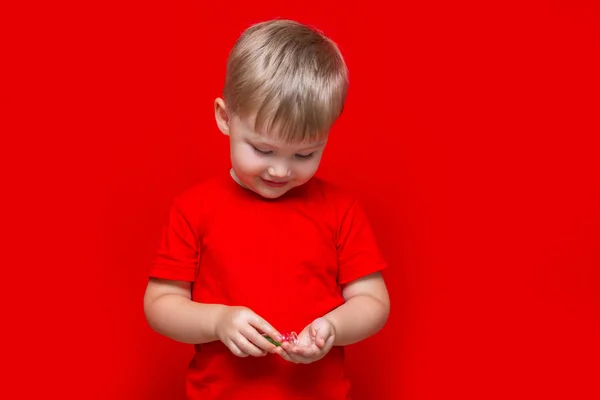 Μικρό παιδί αγόρι ρίχνει χάπια από τη δυνατότητα στο χέρι, υγιή αντίληψη. Είναι επικίνδυνα δισκία σε μωρά χέρια κόκκινο φόντο — Φωτογραφία Αρχείου