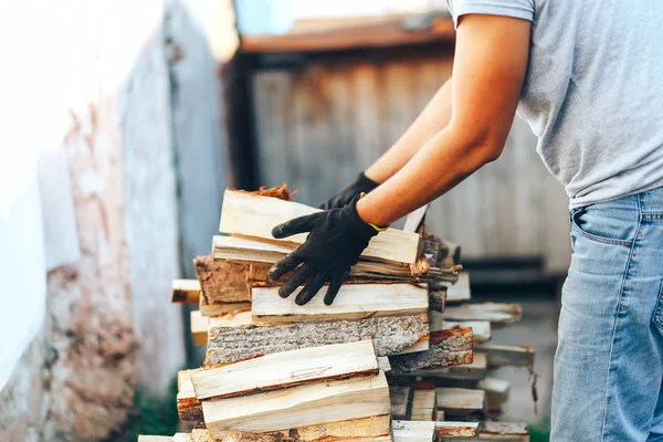 Evi ısıtmak için hazırlanmış bir yığın odun yığını. Kış veya şenlik ateşi için odun toplamak. Adam elinde ateş odun tutar