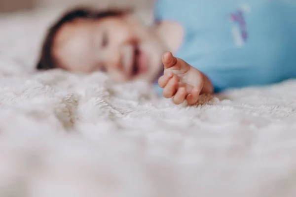 Bambina o ragazzo strisciare sul letto in lenzuola bianche, guardando la fotocamera e raggiungere la madre — Foto Stock