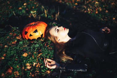 geniş açık gözleri ve elinde bir kabak ile açık bir ağız ile siyah deri ceket abartılı makyaj ile güzel genç sarışın kadın