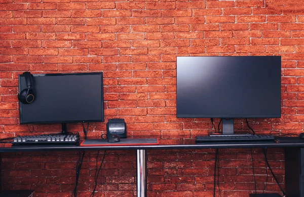 Two computer monitors with black screen on a desk, one workplace on table for two people