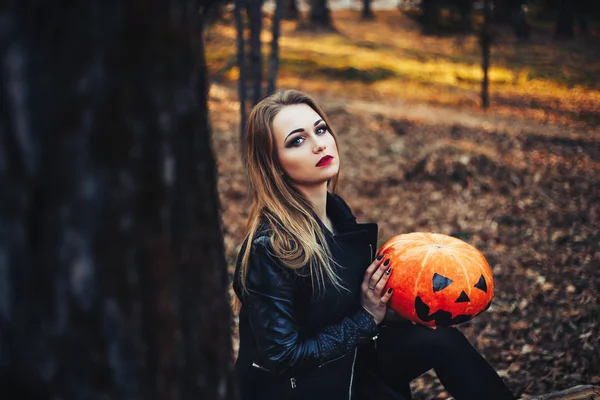 Piękna Nowoczesna wiedźma trzyma halloweenową dynię w lesie. Października. Wesołych Świąt — Zdjęcie stockowe