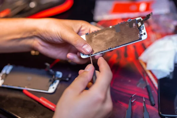 Чоловік ремонтує мобільний телефон. В кадрі, його руки і деталі пристрою. ремонт магазину для гаджетів — стокове фото