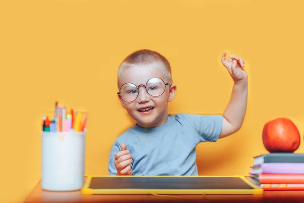 Niño pequeño pintando y haciendo deberes en su escritorio teniendo una idea, concepto de inspiración. volver a la escuela sobre fondo amarillo — Foto de Stock