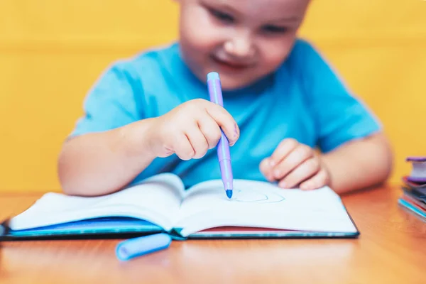 Liten pojke målning och gör hemuppgifter på hans skrivbord, inspiration koncept. tillbaka till skolan på gul bakgrund — Stockfoto