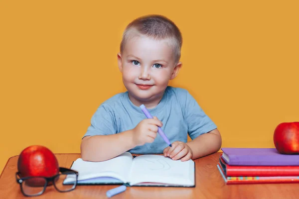 Bambino che dipinge e fa i compiti sulla scrivania, concetto di ispirazione. torna a scuola su sfondo giallo — Foto Stock