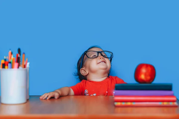 Happy cute sprytna dziewczyna siedzi przy biurku w okularach. Przedszkole dziewczyna w okularach. Wczesna Edukacja — Zdjęcie stockowe