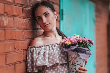 Kırmızı tuğla duvara yakın açık poz begie nokta elbise güzel genç esmer