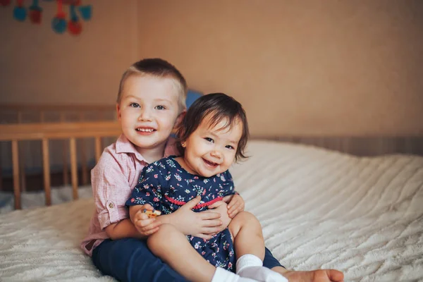 Küçük kardeş 3 yaşında ve kız kardeşi yatakta sarılma 1 yıl — Stok fotoğraf