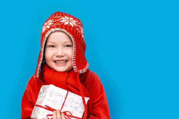 Retrato de un niño feliz sosteniendo un nuevo regalo de Navidad con cinta roja en ropa roja. feliz año nuevo, feliz Navidad —  Fotos de Stock