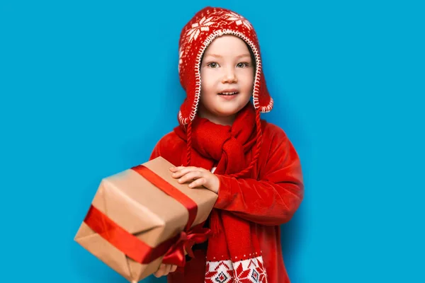 En Navidad. niño con Santa Claus Sombrero celebración de regalo de Navidad con cinta roja y wery cara sorprendida con la boca abierta —  Fotos de Stock