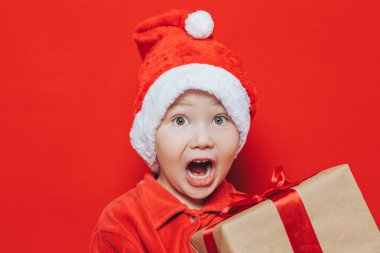 Küçük çocuk elinde Noel hediyesi tutuyor.