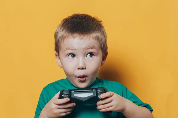 Menino pequeno com joystick no fundo amarelo — Fotografia de Stock