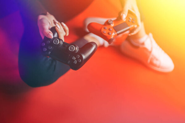 Young woman playing with two gamepads on red.