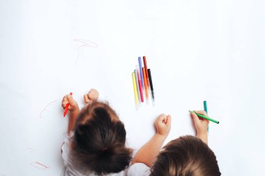 Yetenekli çocuklar beyaz kağıda renkli keçeli kalemlerle resim çizerler, dersler, farklı yaşlardaki çocuklarla görevler. düz yatış, üst görünüm