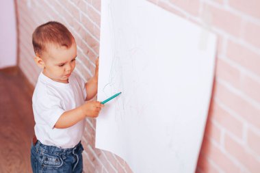 Küçük çocuk kağıda resim çizer, evde eğitim, anaokulu eğitimi..