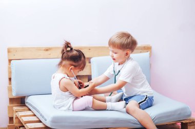Küçük çocuklar steteskopla doktorculuk oynuyorlar, çocuklar için eğitim, geleceğin doktorları..