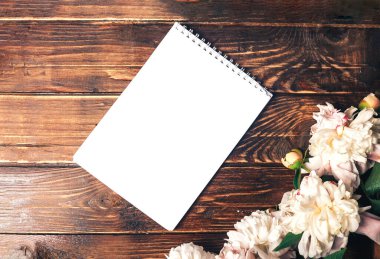 Güzel, narin şakayıklar ve ahşap arka planda beyaz bir sayfa, çiçek açan çiçekler, 8 Mart, anneler günü.