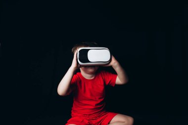 Küçük Çocuk siyah arka planda ışık efektleriyle sanal gerçeklik yaşıyor..
