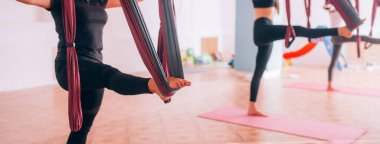 Güzel genç kızlar hamaklarda yoga yapıyorlar, bacaklarını esnetiyorlar, sağlıklarına dikkat ediyorlar..