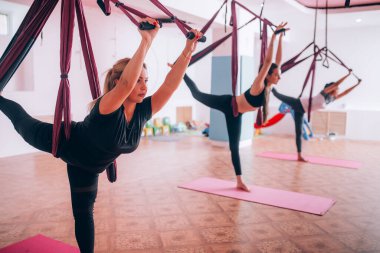 Güzel genç kızlar hamaklarda yoga yapıyorlar, bacaklarını esnetiyorlar, sağlıklarına dikkat ediyorlar..