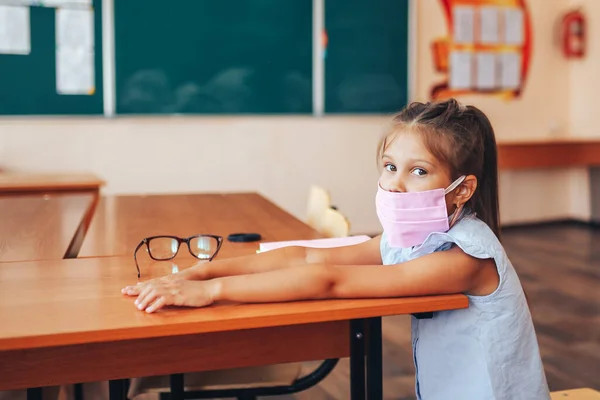 Duas Alunas Máscaras Médicas Estão Sentadas Uma Mesa Escola Opostas — Fotografia de Stock