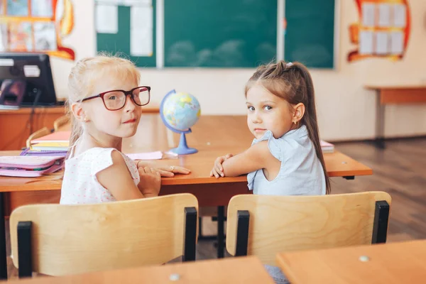 Två Skolflickor Sitter Vid Ett Skrivbord Och Vänder Sig Och — Stockfoto