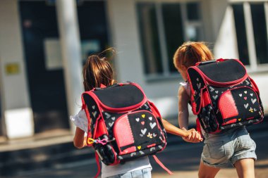 El ele tutuşan iki liseli kız okula, okula, çocukların ilköğretim eğitimine koşuyor..