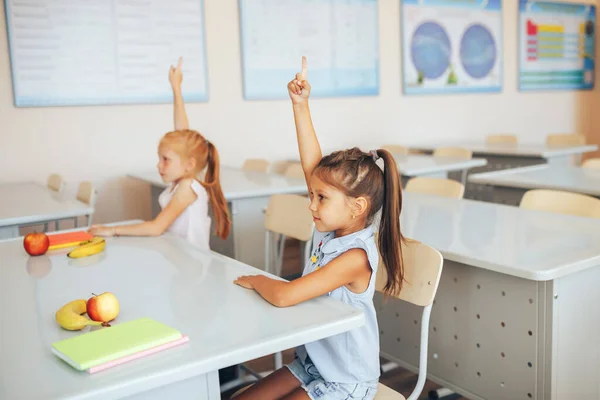 Två Små Skolflickor Sitter Vid Ett Skrivbord Skolklass Och Sträcker — Stockfoto