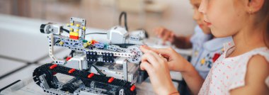 İki liseli kız robotik sınıfında okuyor, bir robot inşaatçısını birleştiriyor..