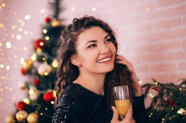 Siyah elbiseli güzel bir kız elinde bardakla elinde içki tutuyor..