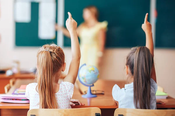 Två Små Skolflickor Sitter Vid Skrivbordet Skolan Och Svarar Lärarens — Stockfoto