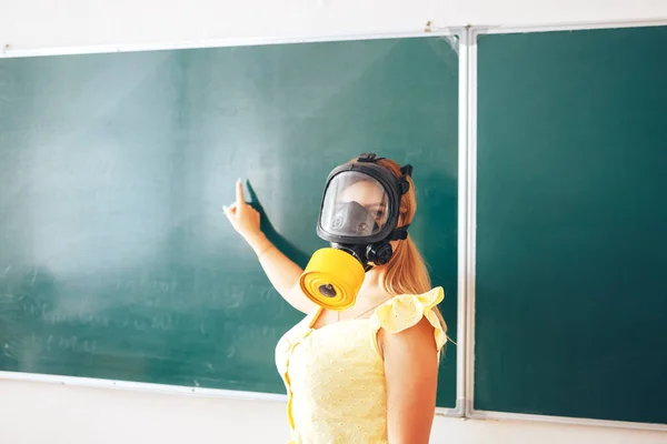 Young teacher in a medical mask holding a pointer in her hand and points to a white board, back to school, modern education, training during the epidemic.