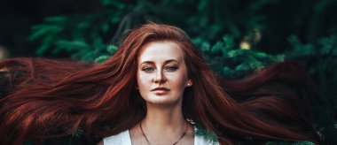 Güzel kızıl saçlı bir kız, Noel ağacının arka planında, bol saçlı, bahar vakti, doğal güzelliği olan..