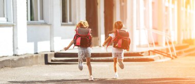 El ele tutuşan iki liseli kız okula, okula, çocukların ilköğretim eğitimine koşuyor..