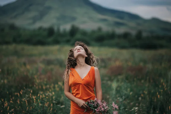 Elinde Bir Buket Çiçekle Turuncu Elbiseli Bir Kız Çimlerin Dağların — Stok fotoğraf