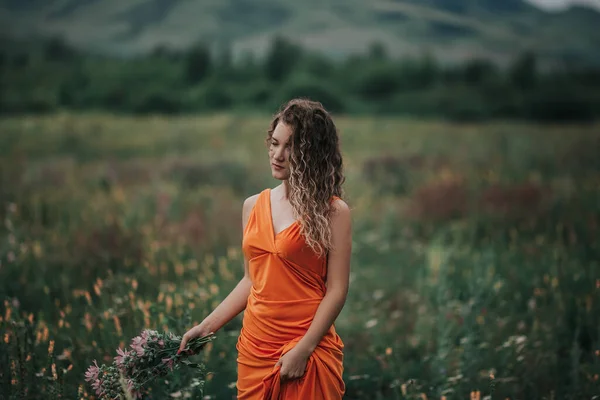 Elinde Bir Buket Çiçekle Turuncu Elbiseli Bir Kız Çimlerin Dağların — Stok fotoğraf