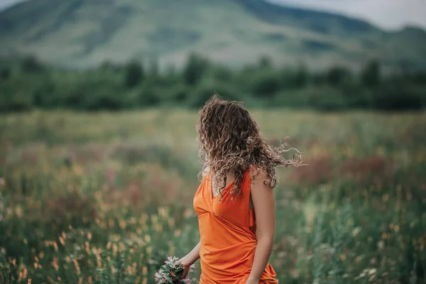Elinde Bir Buket Çiçekle Turuncu Elbiseli Bir Kız Çimlerin Dağların — Stok fotoğraf